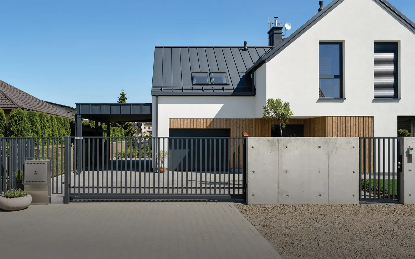 Port med stående sprosser foran et hvitt hus med betongmur