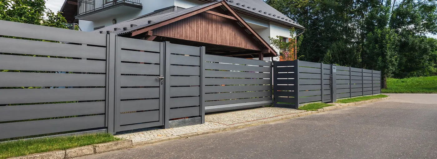 Gangport, skyveport og gjerde i grå aluminium med liggende profiler langs en villavei
